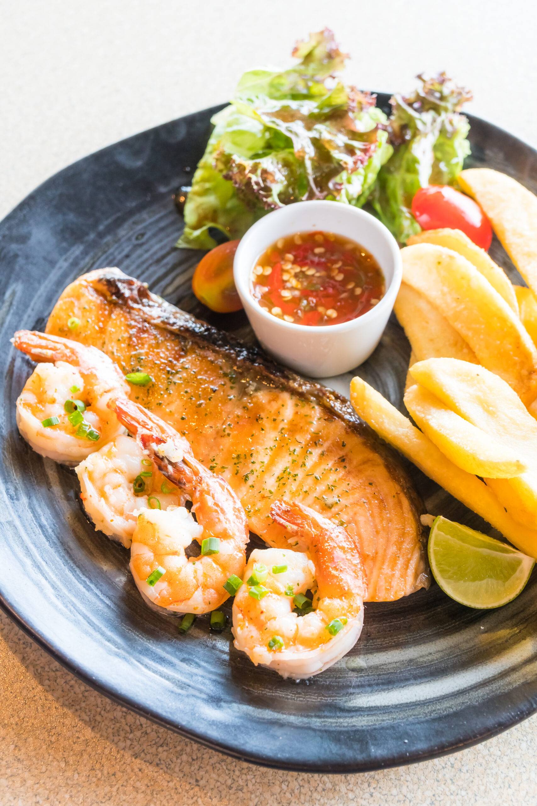 Selective focus point on Grilled salmon and prawn steak in black plate